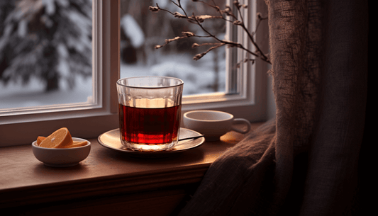 Glühwein auf Fensterbrett und Orangen