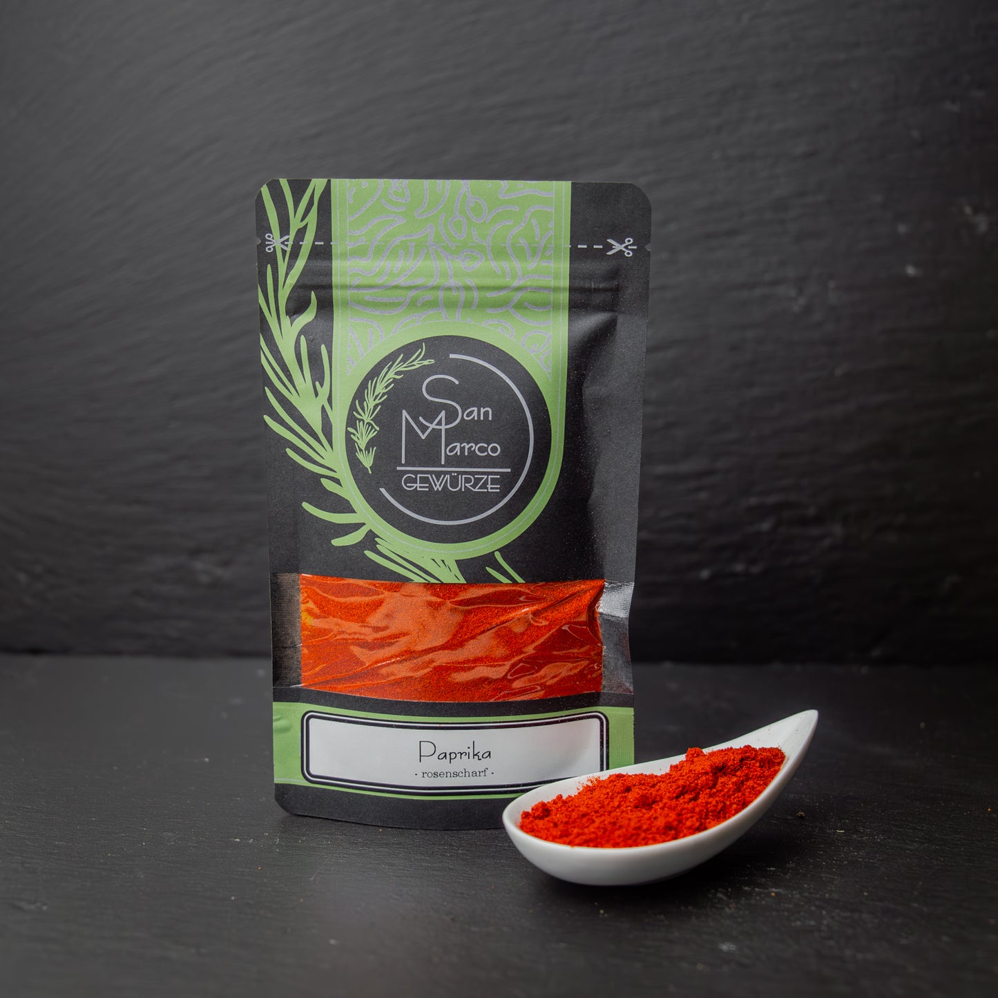 SanMarco Beutel Paprika rosenscharf neben weißer Schale mit rotem Paprikapulver