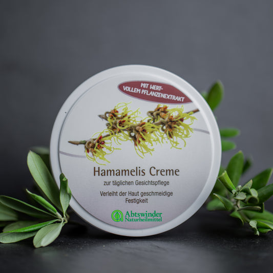 Hamamelis Creme auf dunklem Hintergrund mit grünblättrigen Zweigen