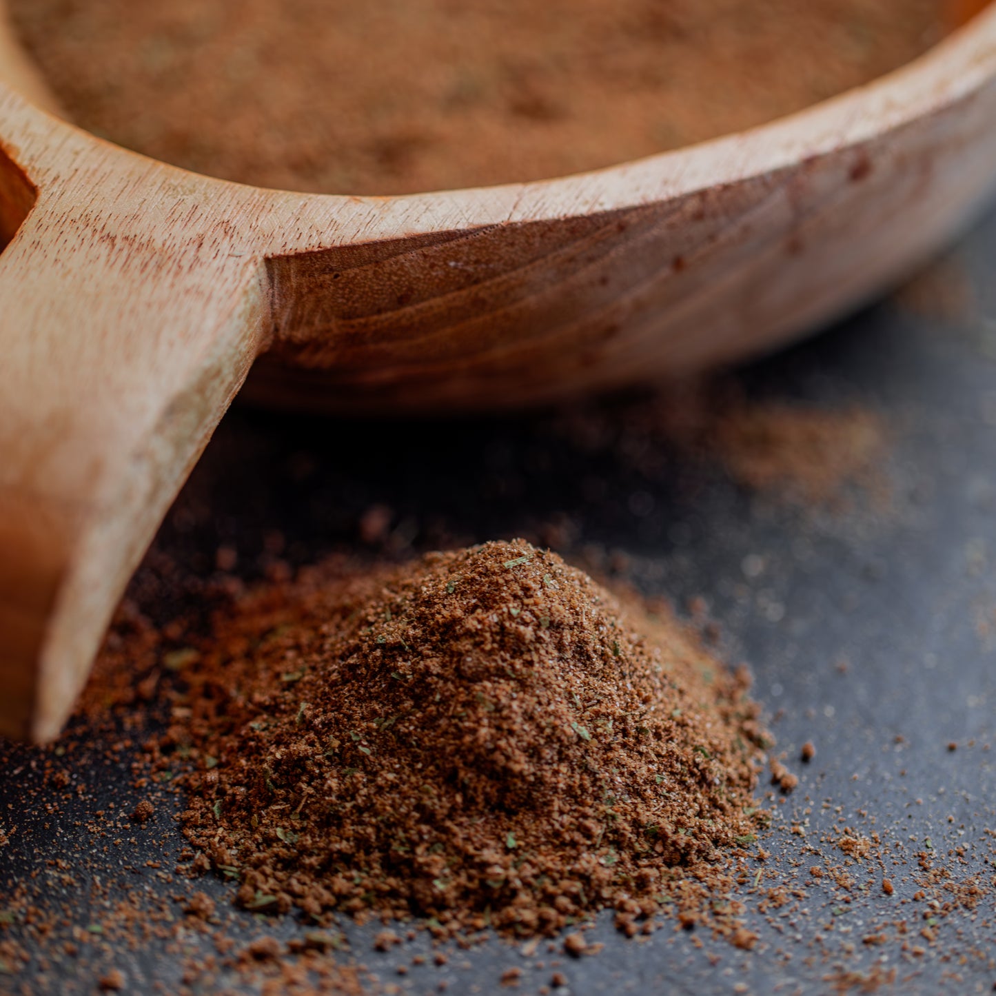 Pilzgewürz auf dunklem Untergrund mit Holzlöffel