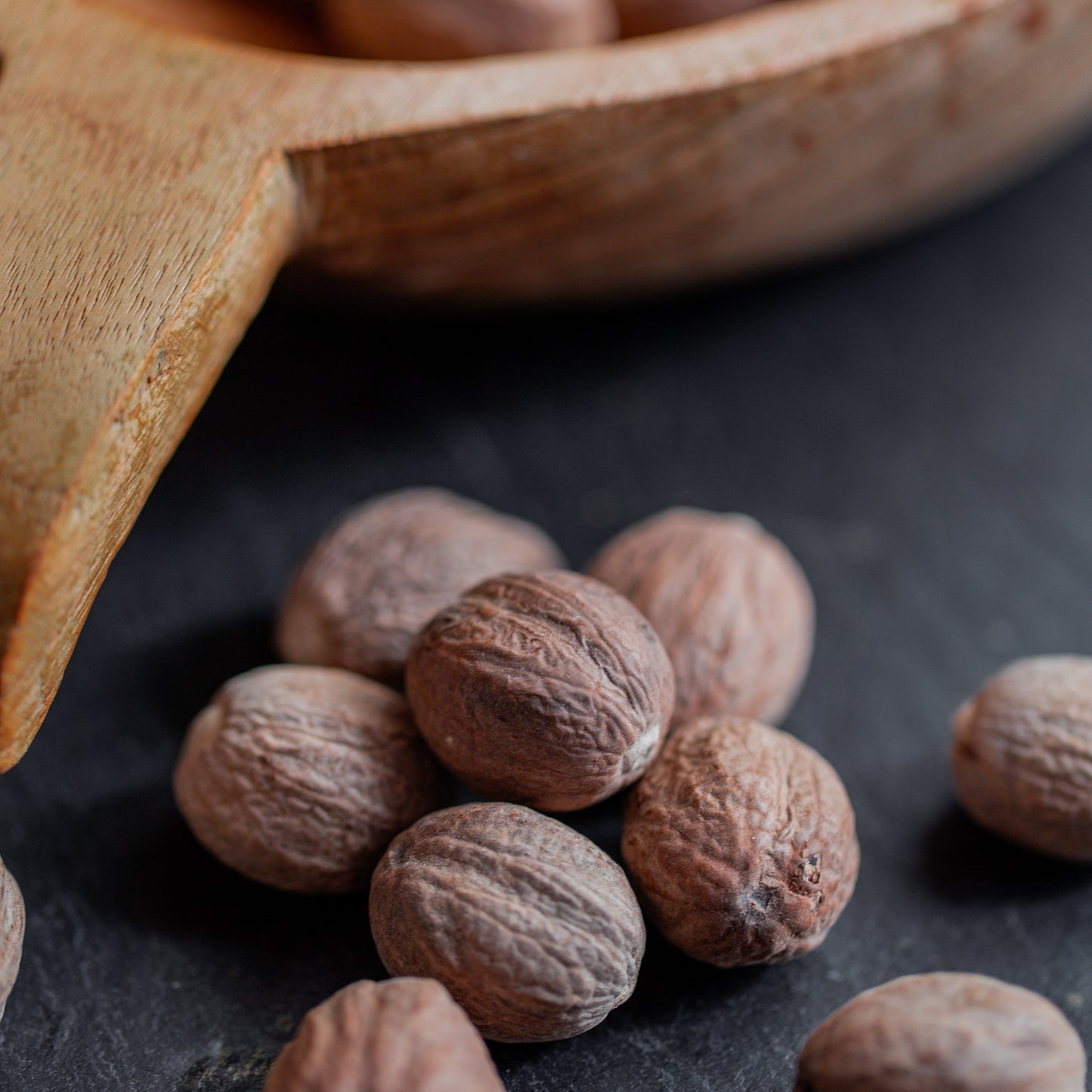 Muskatnuss ganz auf dunklem Untergrund mit Holzlöffel