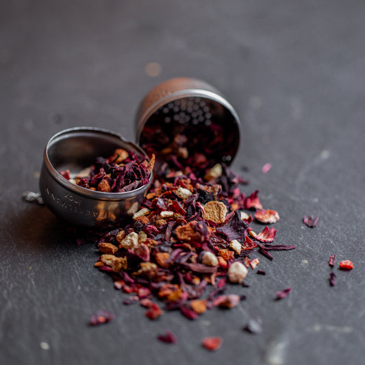 Erdbeer-Himbeer Tee mit Metallsieb auf dunklem Untergrund