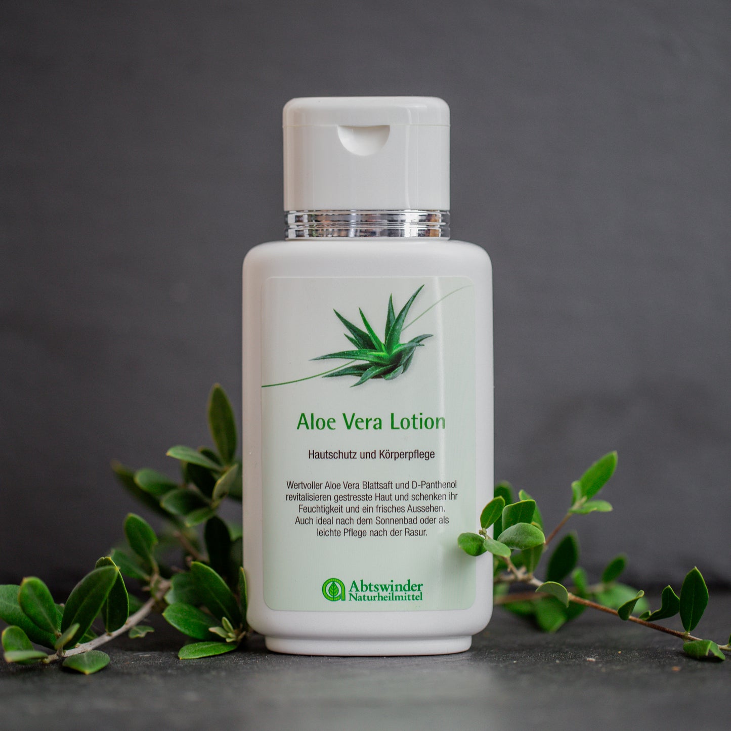 Aloe Vera Lotion auf dunklem Hintergrund mit grünblättrigen Zweigen