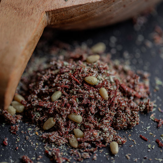 Pesto Rosso Gewürz auf dunklem Untergrund mit Holzlöffel