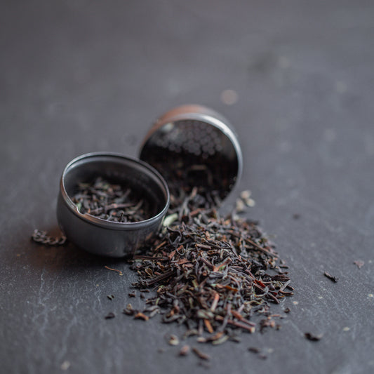 Darjeeling Tee mit Metallsieb auf dunklem Hintergrund