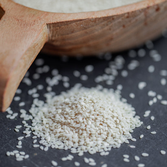 Sesamsaat weiß auf dunklem Untergrund mit Holzlöffel