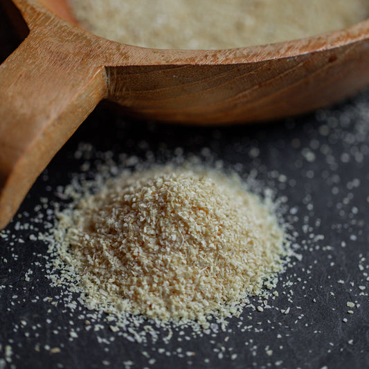 Zwiebelgranulat fein auf dunklem Untergrund mit Holzlöffel